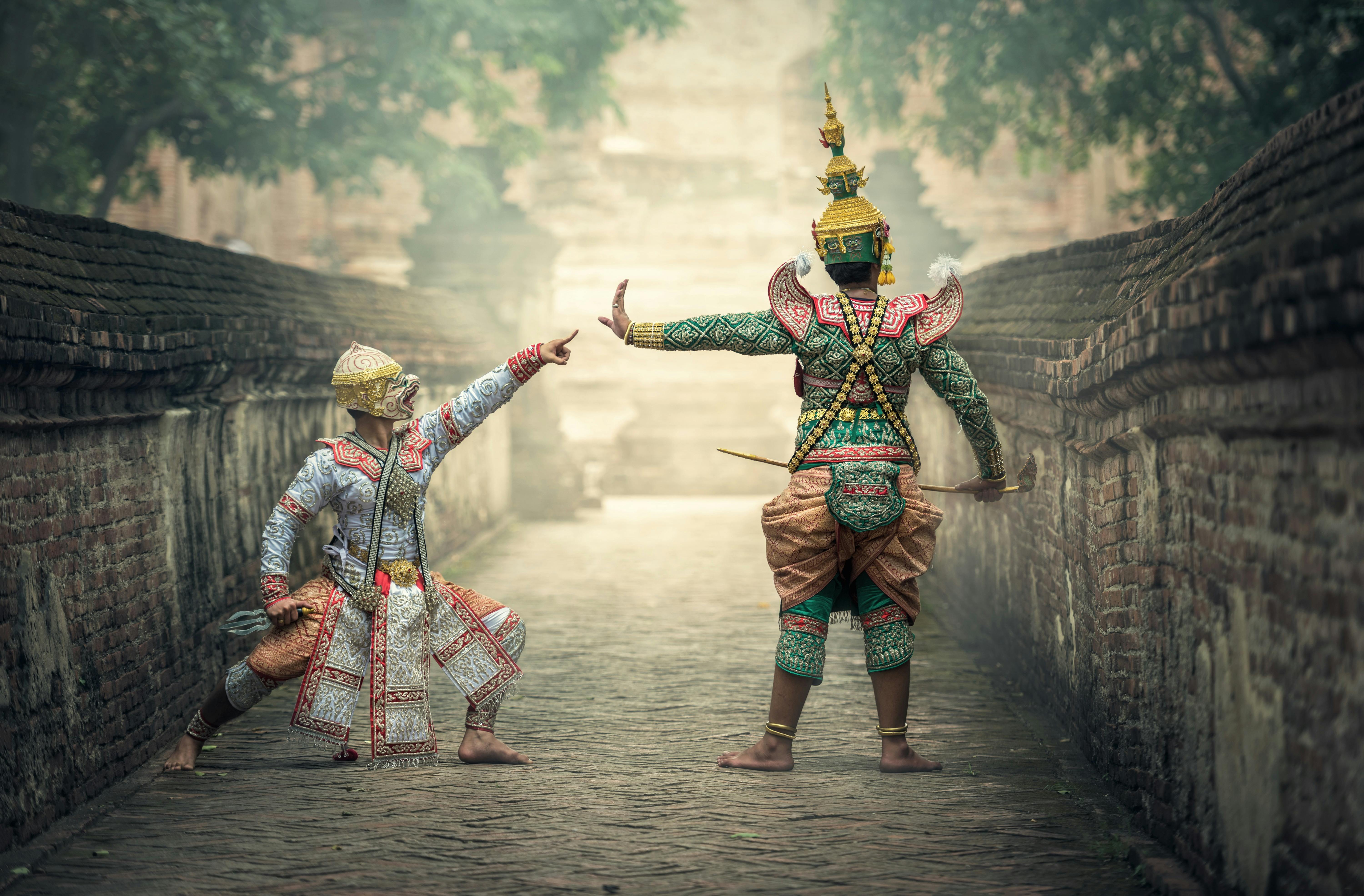 Two performers in vibrant traditional costumes performing a cultural dance outdoors.